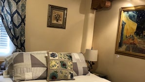A hotel room with a large bed, a ceiling fan, a painting on the wall, and a window with curtains. - Casita I - 2 Bed, 2 Bath (Santa Fe)