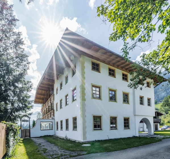Ein mehrstöckiges Gebäude mit weißer Fassade, zahlreichen Fenstern und einem Holzdach.