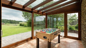 Una mesa de fútbol de mesa en una habitación con ventanas amplias que dan a un área verde.
