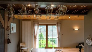 Un comedor con mesa de madera, sillas y una barra con vasos y un candelabro.