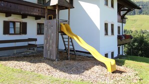 A building with a wooden exterior, a yellow slide, and a climbing wall.