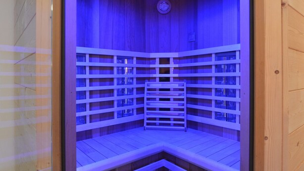 Una sauna con paredes y bancos de madera, equipada con un reloj en el techo.