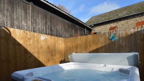 Un jacuzzi en un patio trasero con valla de madera y pared de piedra.