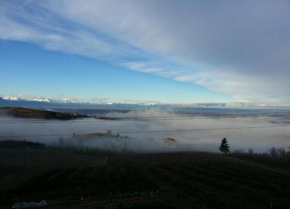 A mountainous landscape with a view of snow-capped peaks in the distance, a body of water in the foreground, and a clear sky above. - Hillview Langhe Apartment (Belvedere Langhe)