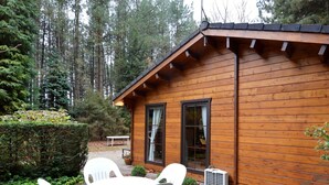 Une cabane en bois dotée d’un patio comprenant une table et des chaises.