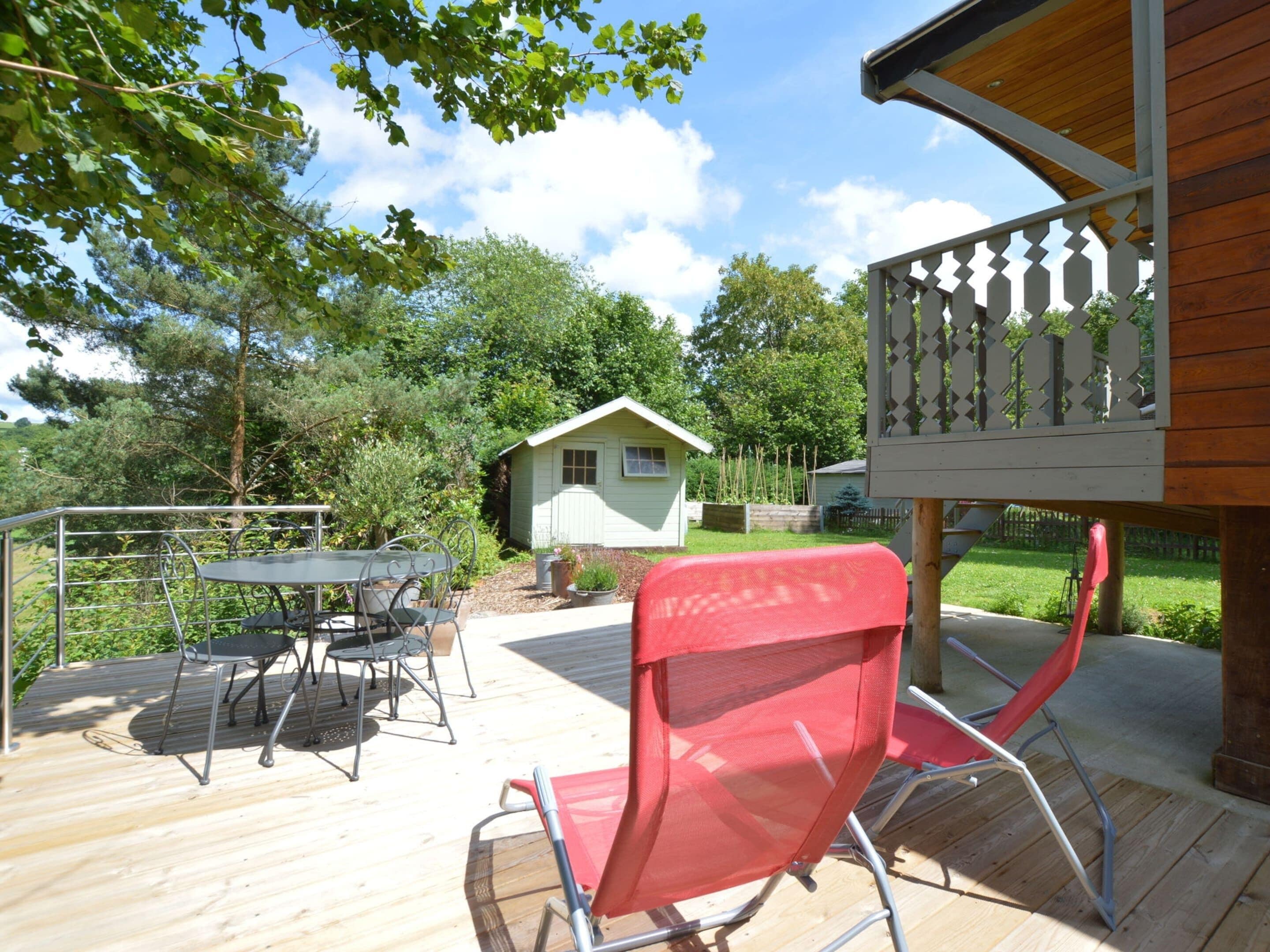 A deck with outdoor furniture, a small shed, and a wooden structure with a balcony.