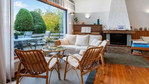 A modern living room with a glass dining table, wicker chairs, a sofa, and a fireplace. - Seeblick-flucht in Langscheid (Sundern)