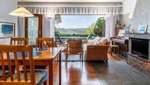 A cozy living room with a dining area, a fireplace, and a scenic view. - Seeblick-flucht in Langscheid (Sundern)