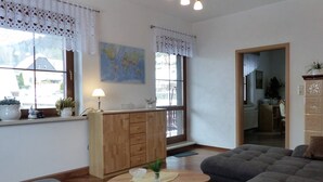 A living room with a sofa, a wooden cabinet, a table with a globe, and a map on the wall. - Cozy Ski Base With Garden (Breitenbrunn/Erzgeb.)
