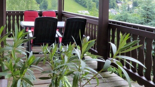 A covered outdoor seating area with a view of a town and greenery. - Cozy Ski Base With Garden (Breitenbrunn/Erzgeb.)