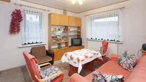 Una sala acogedora con un sofá, sillones, una mesita y un televisor.