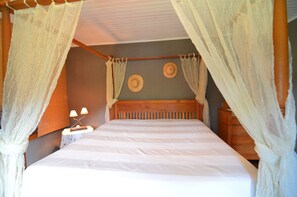 A bed with a canopy, a nightstand with lamps, and a wall with two decorative plates.