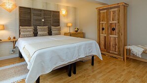 A bedroom with a large bed, wooden wardrobe, and two bedside lamps. - Charming Cottage in a Farm With Views (Doische)