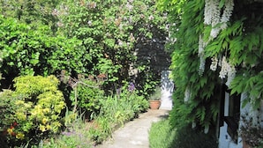 A garden pathway surrounded by lush greenery and flowering plants. - Charming Cottage in a Farm With Views (Doische)