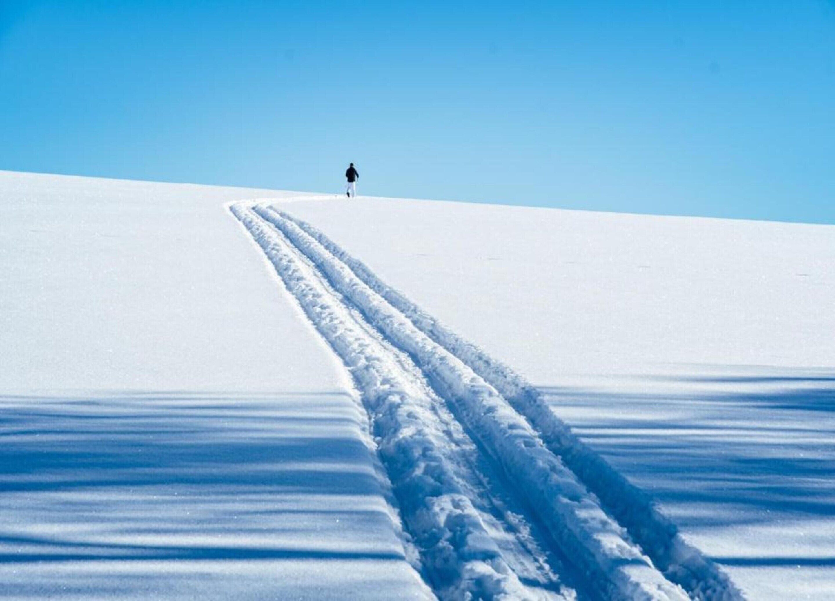 Schneebedeckte Landschaft, eine Person geht vom Betrachter weg.