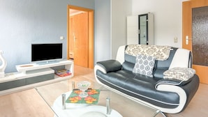 Uma sala de estar com sofá, televisão, armário e porta.