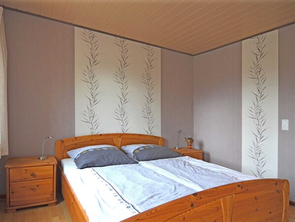 Un dormitorio con una cama de madera, dos mesitas de noche y una pared con un diseño de hojas.
