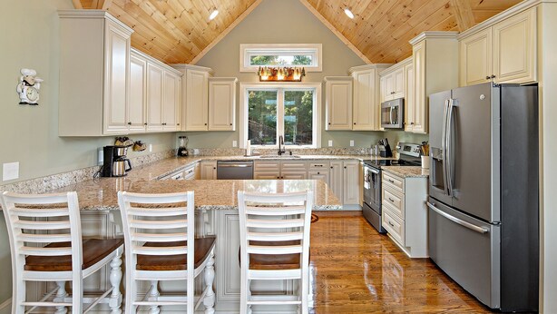 A kitchen with a central island, white cabinetry, a stainless steel refrigerator, and a wooden ceiling. - SMITH TREEHOUSE LAKE LURE: CLOSE TO ASHEVILLE AND TYRON WITH KILLER VIEWS (Mill Spring)