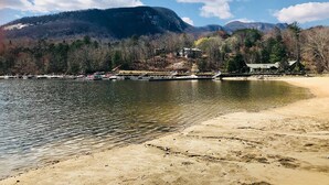 A lakeside view with a sandy beach, boats, and a mountainous backdrop. - SMITH TREEHOUSE LAKE LURE: CLOSE TO ASHEVILLE AND TYRON WITH KILLER VIEWS (Mill Spring)