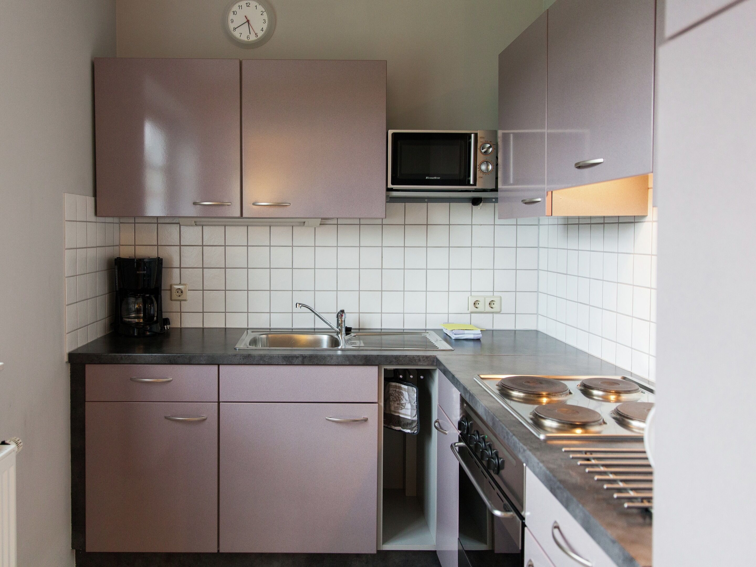 A kitchen with a microwave, stove, sink, and cabinets.