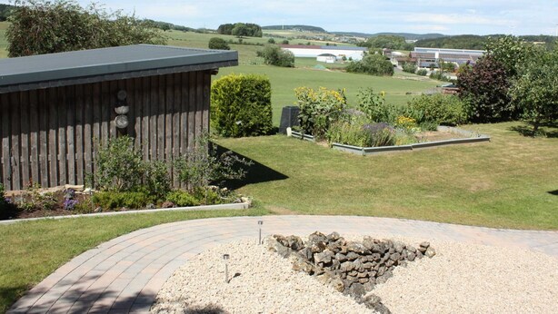 Vue d’une propriété dotée d’un jardin clôturé, d’une construction en bois et d’un espace aménagé avec un foyer extérieur.