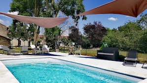 A rectangular swimming pool with clear blue water, surrounded by lounge chairs and umbrellas.