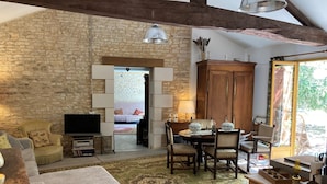 A rustic living room with stone walls, a wooden dining table, and a television.