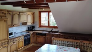 A kitchen with wooden cabinets, a microwave, a coffee maker, and a window with blinds.