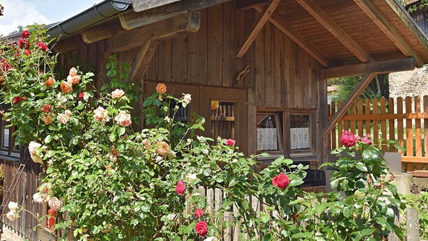 A wooden cabin with a sloped roof, a porch, and a wooden fence. - Ferienhaus mit Garten in Waldnahe (Arnschwang)
