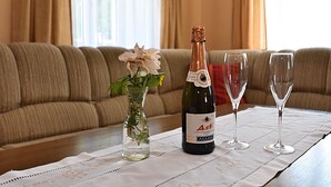 A table with a bottle of wine, a glass, and a vase with flowers. - Ferienhaus mit Garten in Waldnahe (Arnschwang)