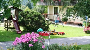 A playground with a slide, swings, and a small boat. - Ferienhaus mit Garten in Waldnahe (Arnschwang)