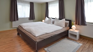 A modern bedroom with a large bed, bedside tables, and a window with curtains. - Ferienhaus mit Garten in Waldnahe (Arnschwang)
