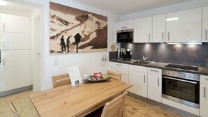 Une cuisine moderne avec des meubles blancs, des appareils en acier inoxydable et une table à manger en bois.