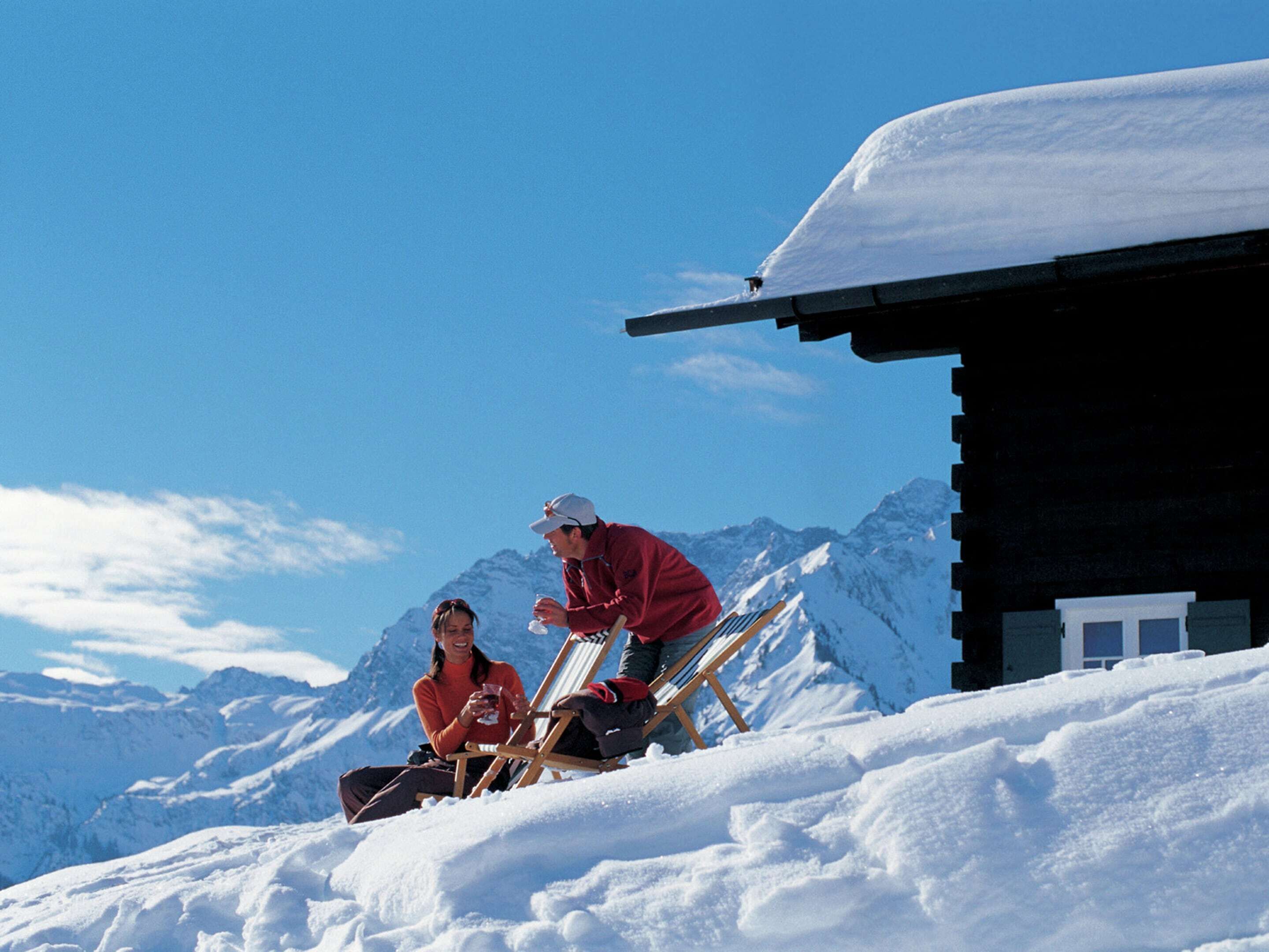 A snowy mountain scene with a wooden cabin and a chair.