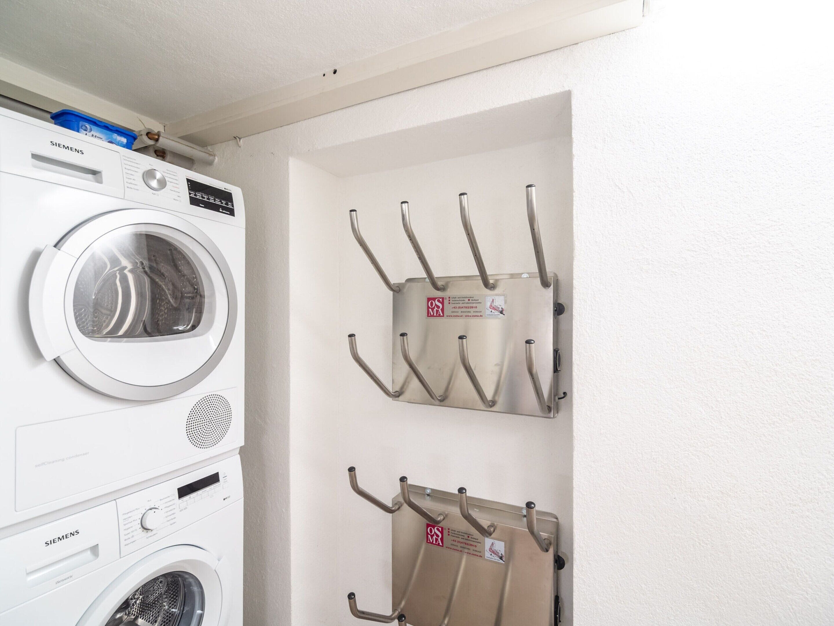 A laundry area with a Siemens washing machine and a wall-mounted drying rack.