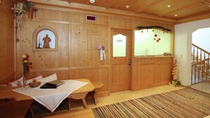 En interiör med träpanel, ett matbord, bänkar, ett litet altare och en trappa.
