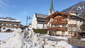 Ett hotell i traditionell alpnisk stil, med ett markant kyrktorn och ett snötäckt landskap.