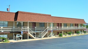 A motel with a brick facade, multiple rooms, and a parking lot. - Country Meadow inn (South Lyon)