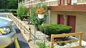 A hotel with a balcony, a sign indicating parking for managers only, and a vehicle parked in front. - Country Meadow inn (South Lyon)