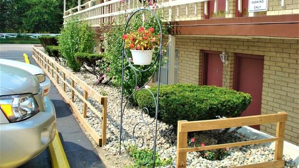 A hotel with a balcony, a sign indicating parking for managers only, and a vehicle parked in front. - Country Meadow inn (South Lyon)