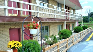 A motel with a balcony, a hanging flower pot, and a wooden fence. - Country Meadow inn (South Lyon)