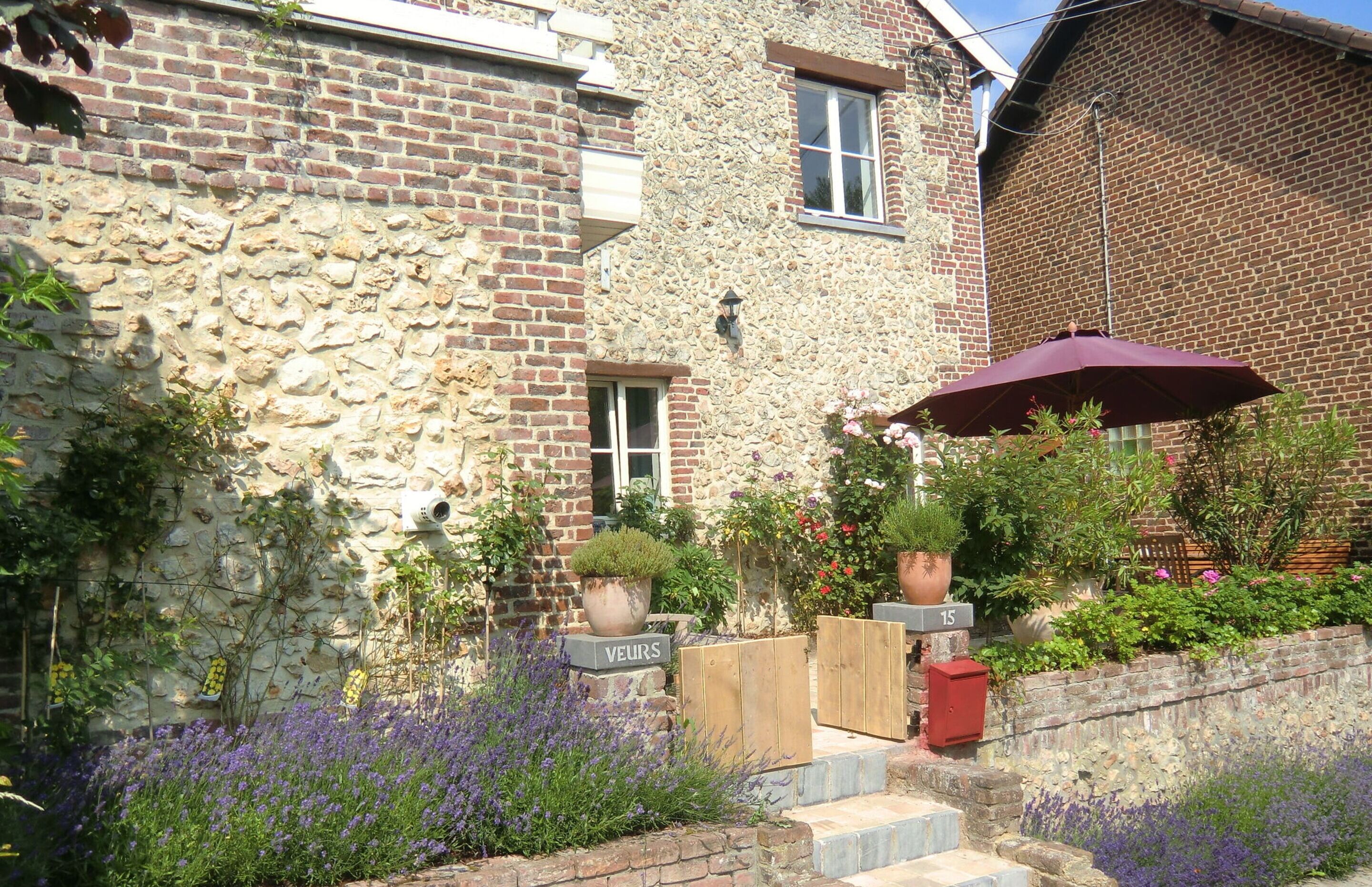 Un bâtiment en pierre avec une partie en briques, une porte en bois portant l’inscription « VELURS » et une boîte aux lettres rouge.