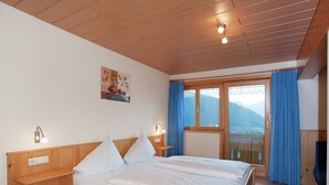 Una cama de madera en una habitación con vistas a las montañas a través de un amplio ventanal.
