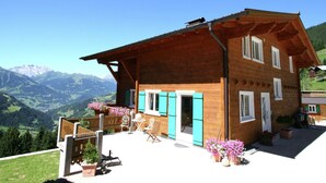 Un chalet de madera con balcón que da a un paisaje montañoso.