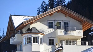 A multi-story building with a balcony, a ski lift, and a snowy landscape.