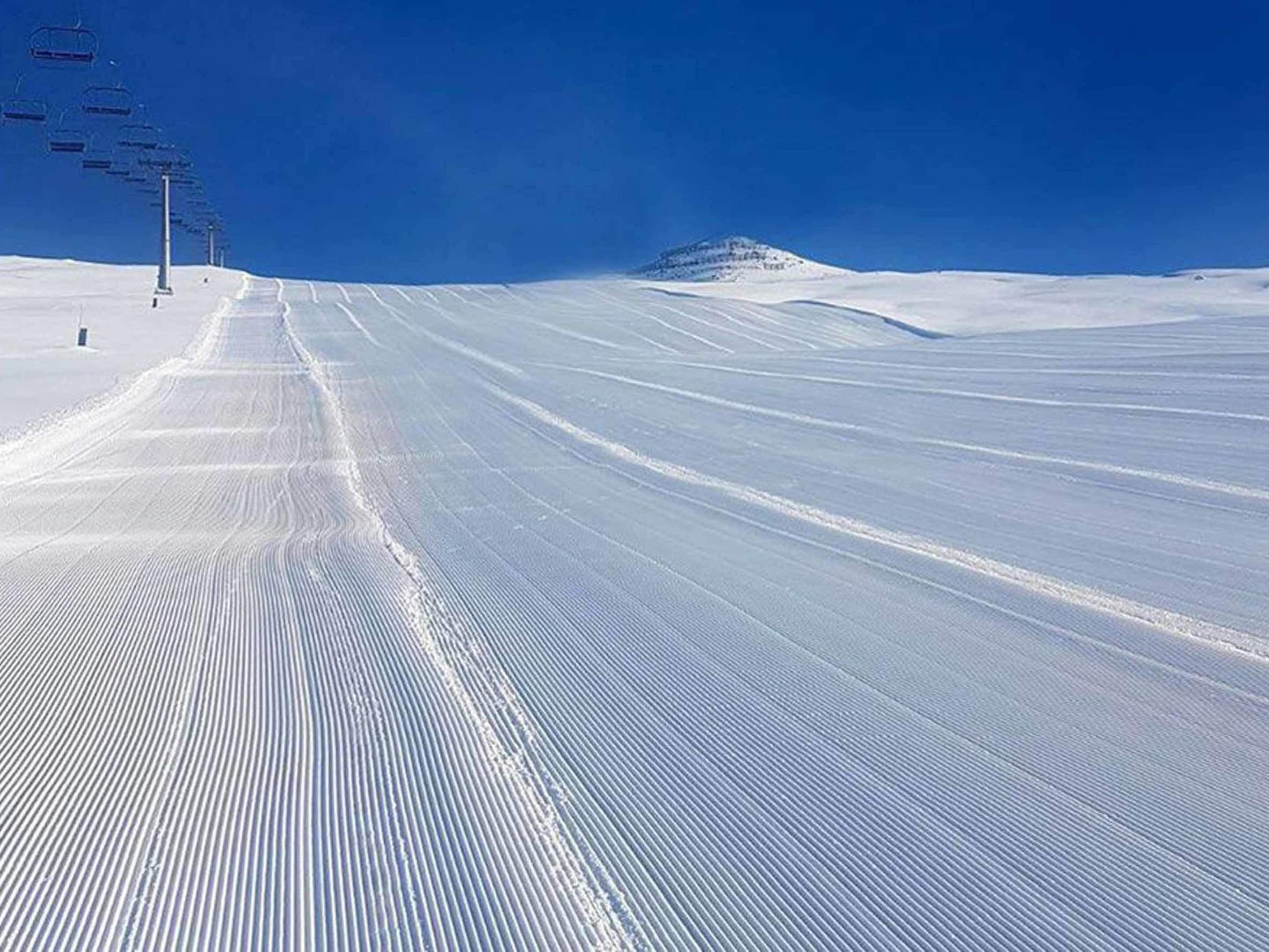 A snow-covered ski slope with ski lifts in the background.