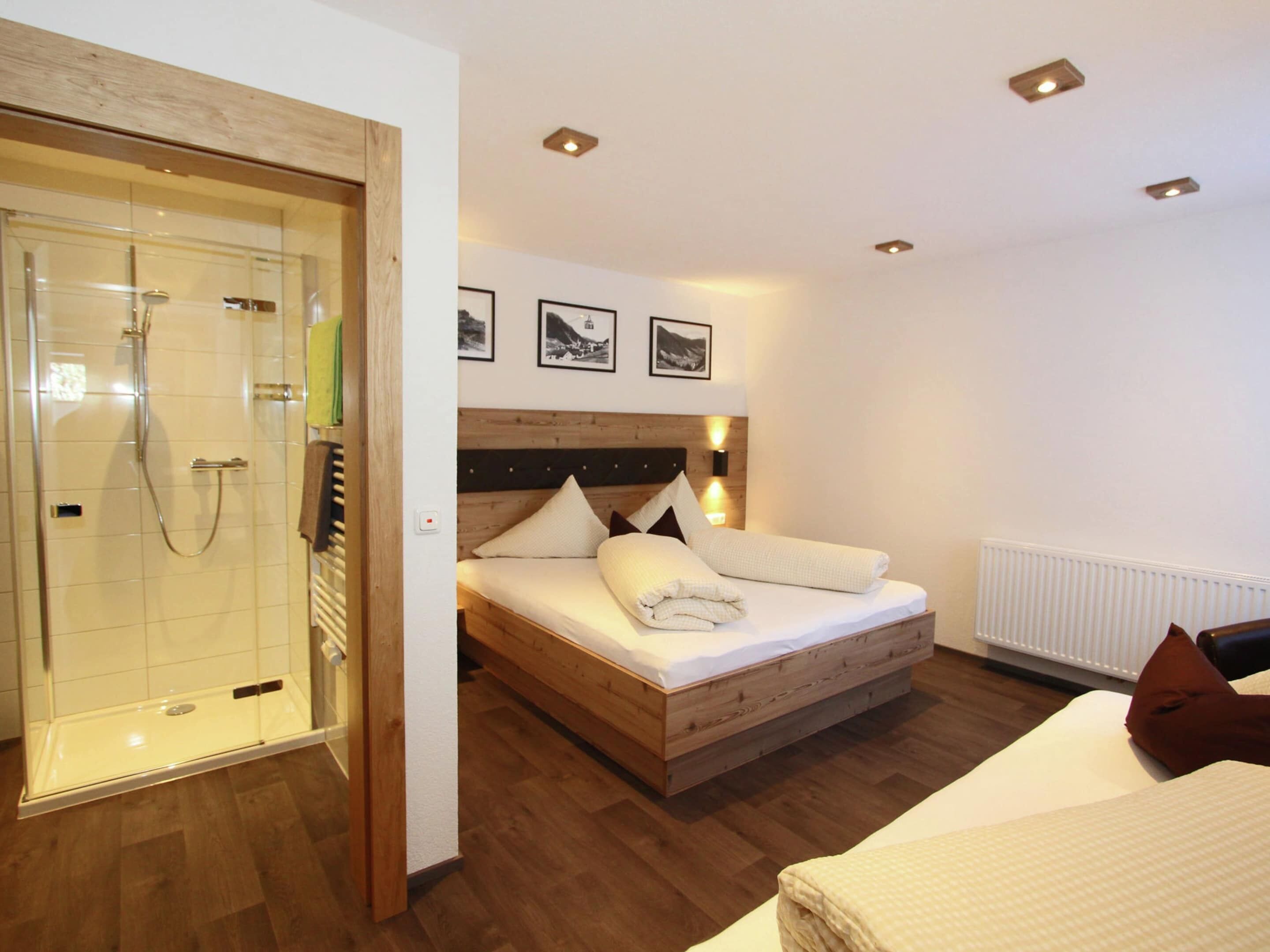 A bedroom with a wooden bed, a glass shower enclosure, and a white radiator.