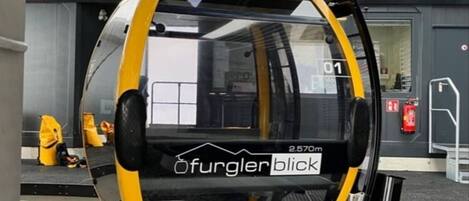 A yellow and black vehicle with "Ofurgerlblick" and "2.570m" text, parked outside a building with a fire extinguisher and a door marked "01".