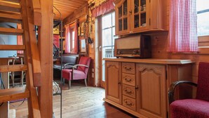 A wooden cabin interior with a dining area, a red upholstered chair, a cabinet with glass doors, and a vintage radio. - Chalet Near Lake Klopeiner With Sauna (Feistritz ob Bleiburg)