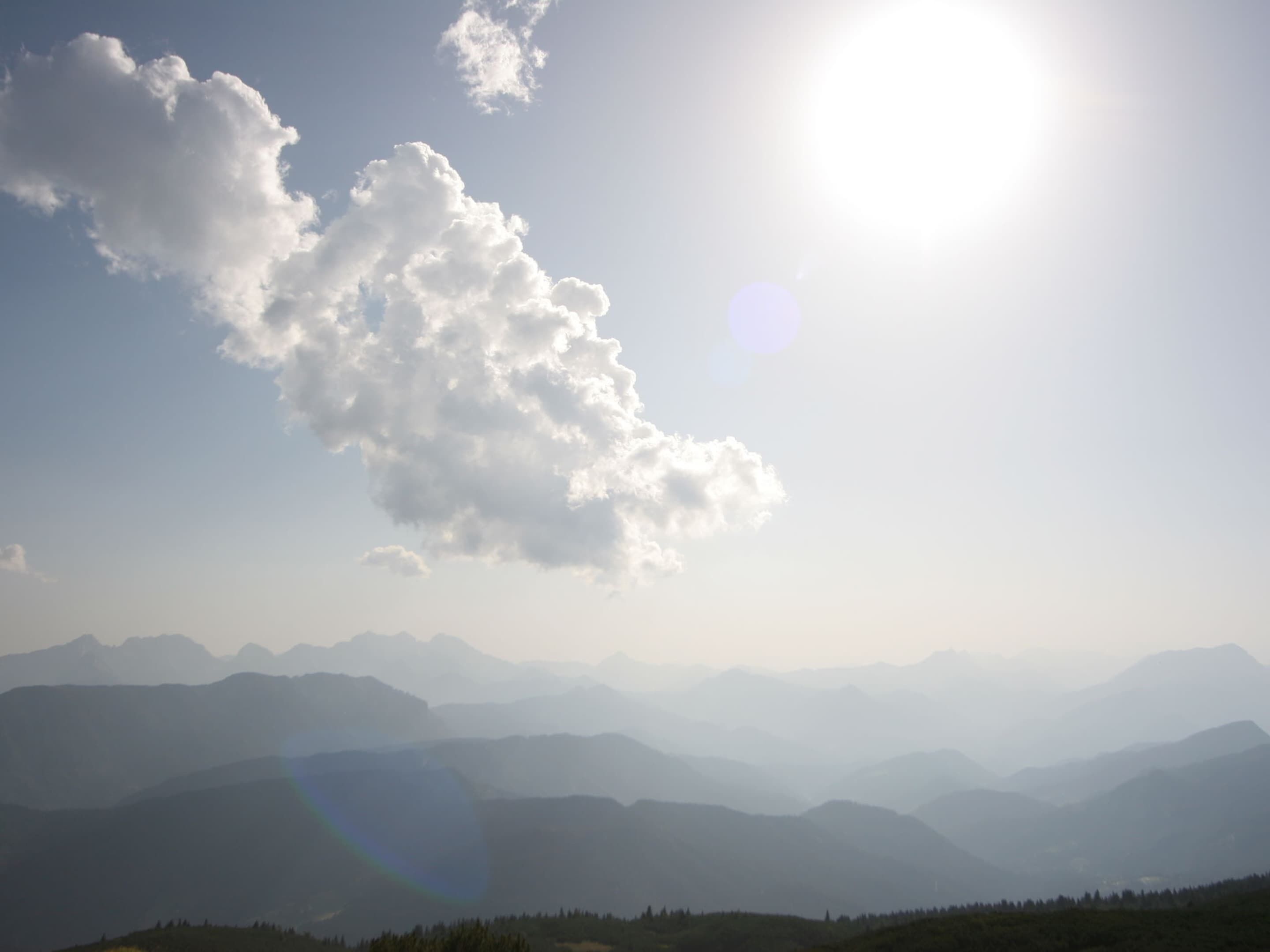 Eine Berglandschaft mit blauem Himmel und einer großen Sonne.